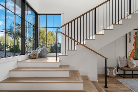 The expansive mullion-styled window adorning the staircase floods the surrounding space with an abundance of natural light. 