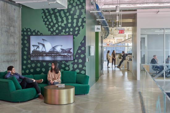 This vibrant hallway corner invites employees to collaborative and functions as a community space centered between modern conference rooms and the open concept office space