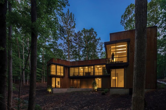 Vast expanses of floor-to-ceiling glass and cantilevered windows overlook the forest behind the house.