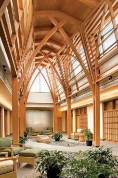 Located at the center of the facility and flanked by the treatment rooms, a peaked glass and wood covered garden courtyard is a quiet meditation area. Planted with a garden and with a water wall at one end, the courtyard also features the arched wooden truss work seen along the entry loggia and in the circular library. Two different moods can be created for this quiet room. By day dimmable 3000K fluorescent coves located along the perimeter above the treatment room doors give an uplifting feel to the space.