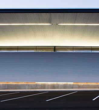 Material transitions on the façade are distinguished by linear bands of light.