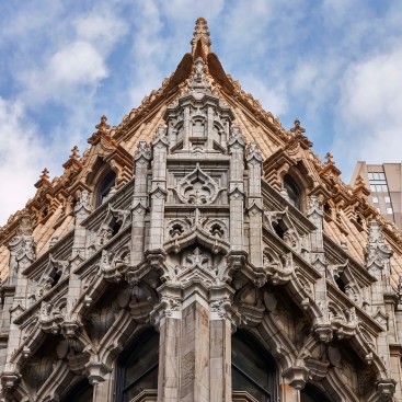 The building exterior is made of carved light grey sandstone and terra cotta. Ornamental features on the upper mansard roof and dormers were restored and repaired, including replacement of many terra cotta roof tiles and new roofing and flashing.