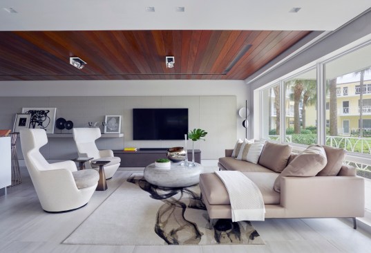 In the middle of the sitting area, a coffee table also from Holly Hunt, humbly brings the outside in with its orb concrete stone-like shape, minted in varying textures and different shades of gray. Beneath, an off-white area rug with a deep gray smokey pattern from The Rug Company brings the space together with an added layer of texture, creating a contemporary yet cozy allure.