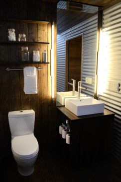 The bathroom features corrugated metal walls.