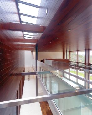Upstairs, a sleek glass bridge crosses over the great room, linking the two sleeping wings.