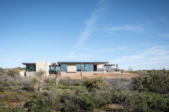 West view of the home. Exterior, motorized shade panels are hidden in the roof soffit above allowing an unencumbered view of the mountains beyond.