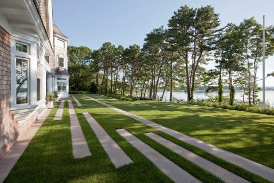 The house sits beyond the 50-foot coastal setback. A fescue lawn slopes gently toward the water between granite steps. The pavement area is just big enough to accommodate the planned furniture layout.