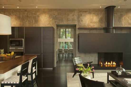 Thomas choreographed the floor plan so that framed outdoor views, such as this sightline from the kitchen through the dining room, appear within openings in the concrete.