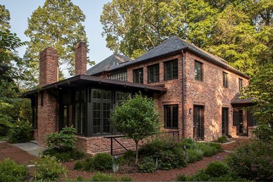 The first-floor family room connects to a two-story addition beyond. New brick walls and walkways integrate the addition into the landscape.