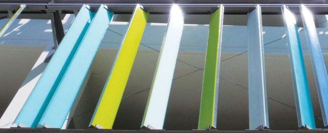 By day the sun saturates the color of the façade's glass channels ...