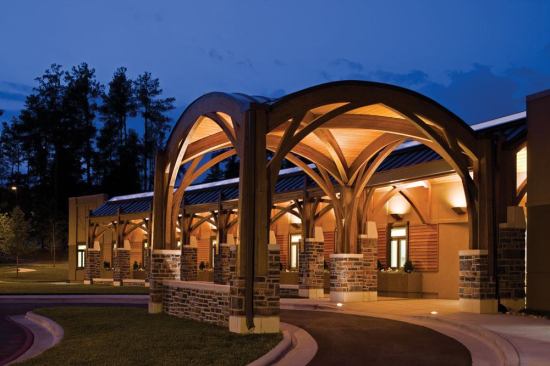 The illumination of the domed entry canopy is produced by 70W 3000K metal halide in-grade adjustable uplights with integral baffles to reduce glare form the source. Located close to the corner piers the warm flood uplighting highlights the wood material while providing a welcoming atmosphere and a comfortable light level.