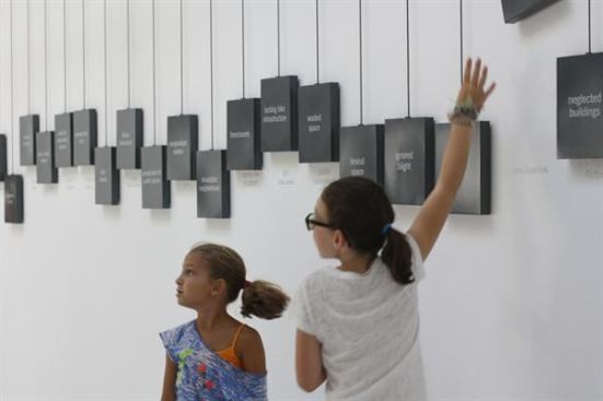 Young visitors to the U.S. Pavilion check out the banner counterweights along the gallery wall.