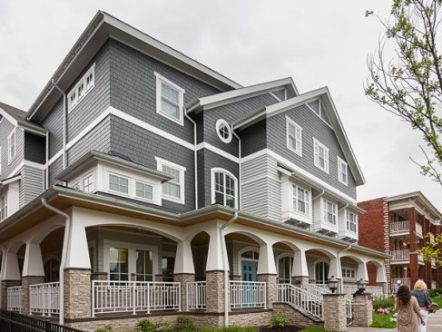 The exterior of the house is anchored by natural stone around the base and a wrap around covered porch that reflect the historical residential architecture of the area.