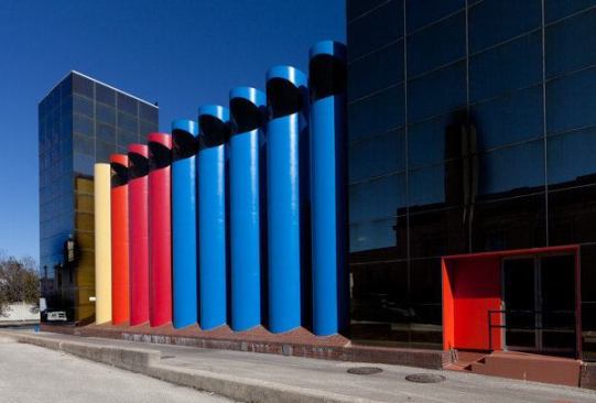 Nine+brightly+colored+ventilation+ducts+liine+a+rear+alley+behind+the+facility.+