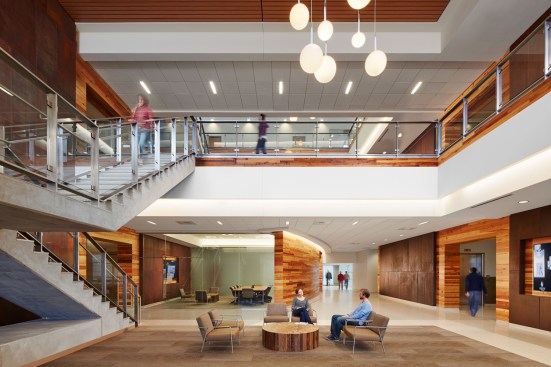 Once inside, visitors are greeted by a bright and open three-story atrium featuring reclaimed-wood walls, digital displays, a glass-walled conference room, comfortable seating, and a majestic, cantilevered concrete communicating stair.