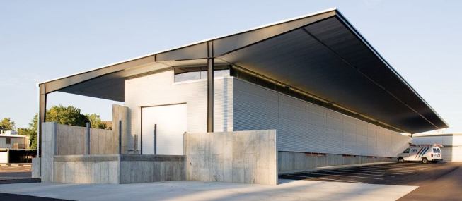By day the warehouse strikes an elegant pose as sunlight helps define the metal Galvalume surfaces.