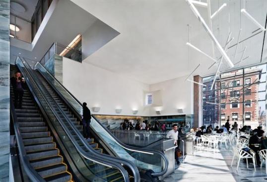 A stair leads to a second-floor caf? that anchors a four-story glazed atrium with escalators to the library and research elevator core above.