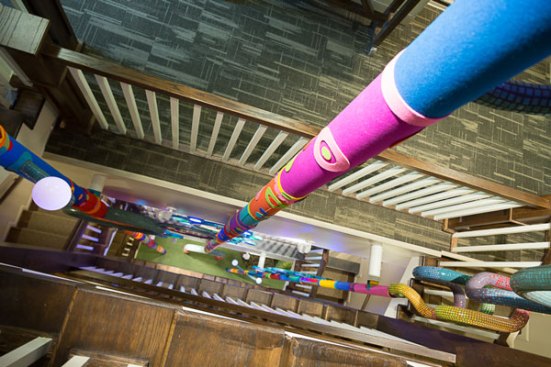 The four-story open stained wood staircase through which pierces the giant, LED-lit stalks of a donor art sculpture that runs from the basement of the house to the roof, designed by local artist Chris Duh.