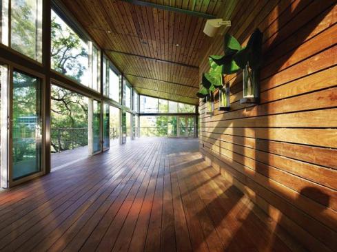 The flexible indoor/outdoor seating area on the second floor is clad on the floor, walls, and ceilings in wood planking that extends outdoors as the decking of the cantilevered balcony. Glass doors allow the seating area to extend out onto the balcony when Houston?s hot, humid climate permits.