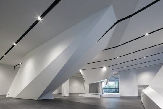 The+ground+floor+forms+a+sort+of+hypostyle+hall%2c+with+the+articulated+ceiling+plane+extending+to+the+ground+to+encase+columns%2c+elevators%2c+and+escalators.+The+stone+tiles+that+line+the+space+are+part+of+the+flooring+detail+system+designed+by+NADAAA%2c+which+aims+to+continue+the+exterior+plaza+into+the+building.