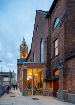 A new glazed addition provides an accessible public entry and space for the box office and main office. The new elevator tower can be seen in the distance with the gabled roof. It sits behind and lower than the bell tower.