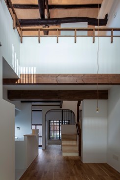View of the double-height dining space. On the upstairs, the original crooked log roof beams are visible.