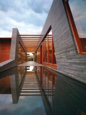 Recycled teak timbers join the garage/guest pod, living pod, and media pod across an outdoor hallway, which slopes gradually into the reflecting pool.