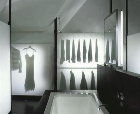 The wardrobe's structural system consists of thin stainless steel posts, which lightly touch the floor and walls, and cantilevered rods and shelving.