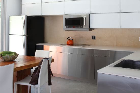 The combined kitchen and dining space gains sunlight from three directions--the oversized patio door, the windows at the top of an open stair, and a glass wall in the living room.