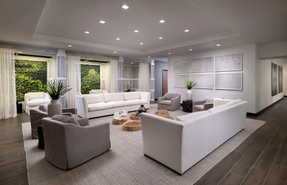 Relaxation lounge with plush white sofas, polished black petrified wood end tables and decorative wooden slabs anchored by lounge rooms with living green walls. 