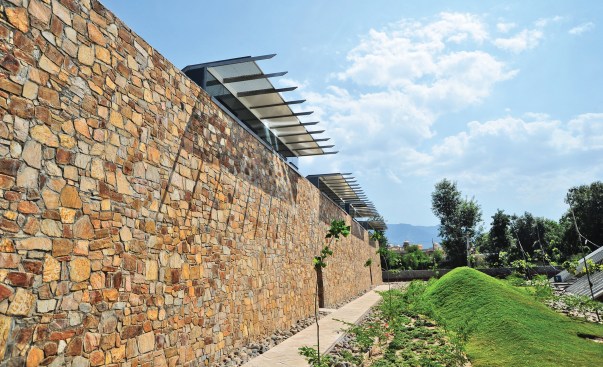 Rubble masonry walls shield the lightweight steel roofs- a strong contrast. 