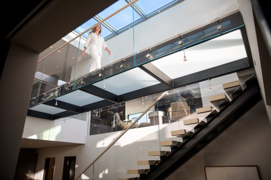Luxury glass bridge walkway stretches under a skylight at Beverly Hills modern home.