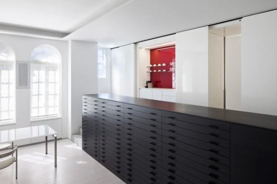 A+solid-looking+white+lacquer+wall+gives+way+to+a+wet+bar+and+entrance+to+a+guest+bedroom.