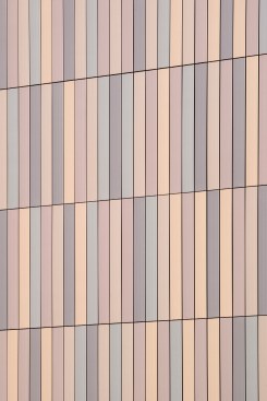 The façade serves a functional and technologically sophisticated purpose yet exhibits artistic expression with a color field of terra cotta that converts light into an active element.  The luminous panels gleam with the full depth of tone that only ceramic glazes can offer. UO Tykeson Hall, OFFICE 52 Architecture, Design Architect.