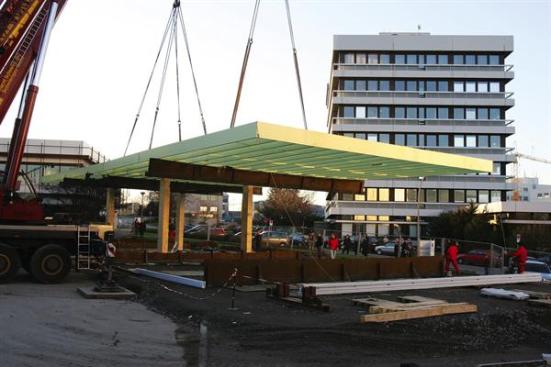 The roof arrived on site in prefab strips, which were bolted together. Then the whole thing was hoisted onto the column pins. When the crane belts were removed, the roof bounced a meter (more than 3 feet) before rocking into place.