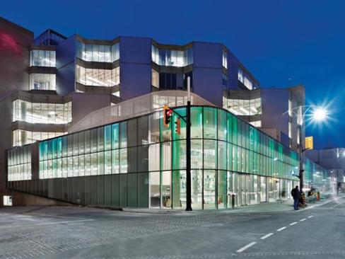 Images of books both opened and closed were abstracted into a frit pattern that, combined with color-changing LEDs, creates a vibrant new fa?ade for the existing Neo-Brutalist structure. The primary entrance to the farmers market (seen here) is on the northeast corner.