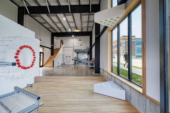 The gallery space features the client’s large-scale kinetic sculptures, set on wood flooring economically salvaged from 18-wheeler tractor-trailers. Passersby can activate the sculptures with a button attached to the outside façade.