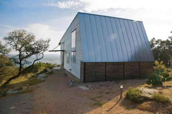 Raw, site-gathered juniper branches and standing-seam metal clad the back of the building.
