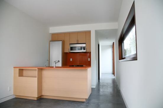 The apartment in the front volume features a long narrow plan and polished concrete floors.