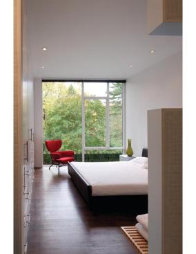 A large window in the master bedroom frames leafy views.