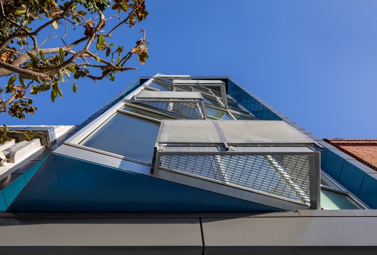 The front-most portion of the building cantilevers over the sidewalk with an obtuse angle.