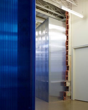 The blue polycarbonate defines the office space edge.  The historic structure is painted white beyond beam number one to improve the lighting reflectivity.  