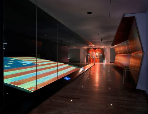 The viewing platform is by design the least illuminated zone in the exhibit dedicated to the Star-Spangled Banner. Finishes were strategically chosen by the design team to ensure that the Star-Spangled Banner could be viewed in a comfortable manner without distractions in the glass surface. The areas leading to and from the viewing area were carefully designed to foster smooth transitions for eye adaptation given the change in light levels.