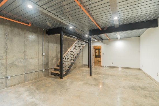 Basement with exposed steel i-beams, laser cut steel stairs, polished concrete floors, radiant heating