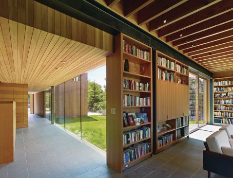 The living spaces in the lower volumes, including the living room, seen here, are all able to be open to the outdoors via sliding low-E glass panels from Cardinal Glass Industries. The floors are lined in Vermont slate, and exposed structural steel along the ceiling plane serves as crown molding.