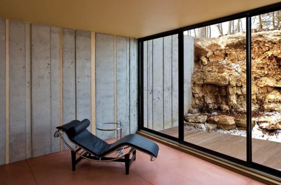 Concrete retaining walls rise out of existing rock outcroppings, strengthening the building's connection to the site.
