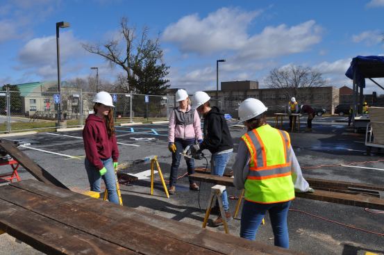 Members of Team Capitol DC cut reclaimed wood boards to size. Pictured, from left to right: Lauren MacGregor (Catholic University of America), Brannon Holman (George Washington University), Katie Simonse (CUA), and Christine Parisi (CUA).