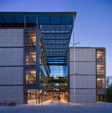 A view of the building entrance. The atrium beyond separates the office and laboratory wings. Photovoltaic panels above are angled to balance energy production, self-shadowing, and solar shading.