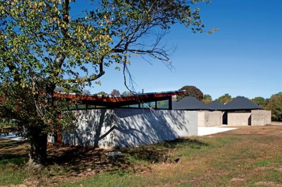 As part of its restoration plan, FMG removed a ramshackle snack bar and replaced it with a new one more sympathetic to Kahn's aesthetic. Located along what was Kahn's planned-but-never-built perimeter wall for the complex, this new pavilion sits within the grid established by the bath house. "The idea is not to in any way upstage it [the bath house] or call undue attention to the new piece," says FMG design partner Michael Farewell. The design for the new snack pavilion was the result of an in-house competition at FMG. Built of concrete block, the structure is the physical inverse of Kahn's bath house pavilions: The butterfly roof form resembles Kahn's pyramidal roof, but flipped upside down. The clerestories are there, but instead of being open to the elements, they are enclosed in glass. And instead of being completely monolithic, the side where food is served is permeated by windows.