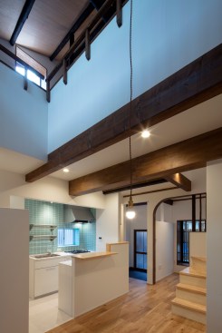 View of the kitchen, entryway, and the TV/guest room seen from the dining space.